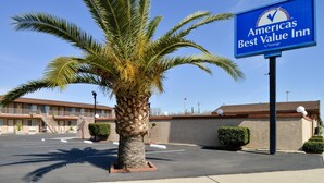 A parking lot with a palm tree and a sign for Americas Best Value Inn.