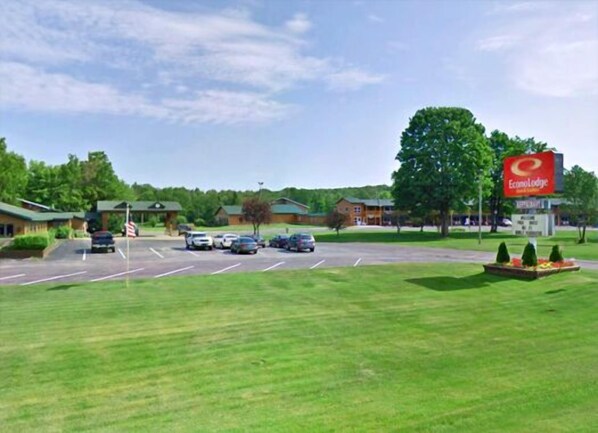 A parking lot with several cars, a building with a red sign reading "Econo Lodge," and a grassy area with trees.
