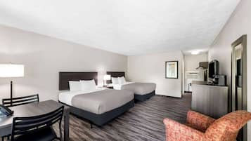 A hotel room with two beds, a desk with a chair, a television, and a small kitchenette.