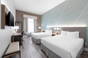 A hotel room with two beds, a desk with a chair, a TV, and a window with curtains. - Comfort Inn & Suites Surrey (Surrey)