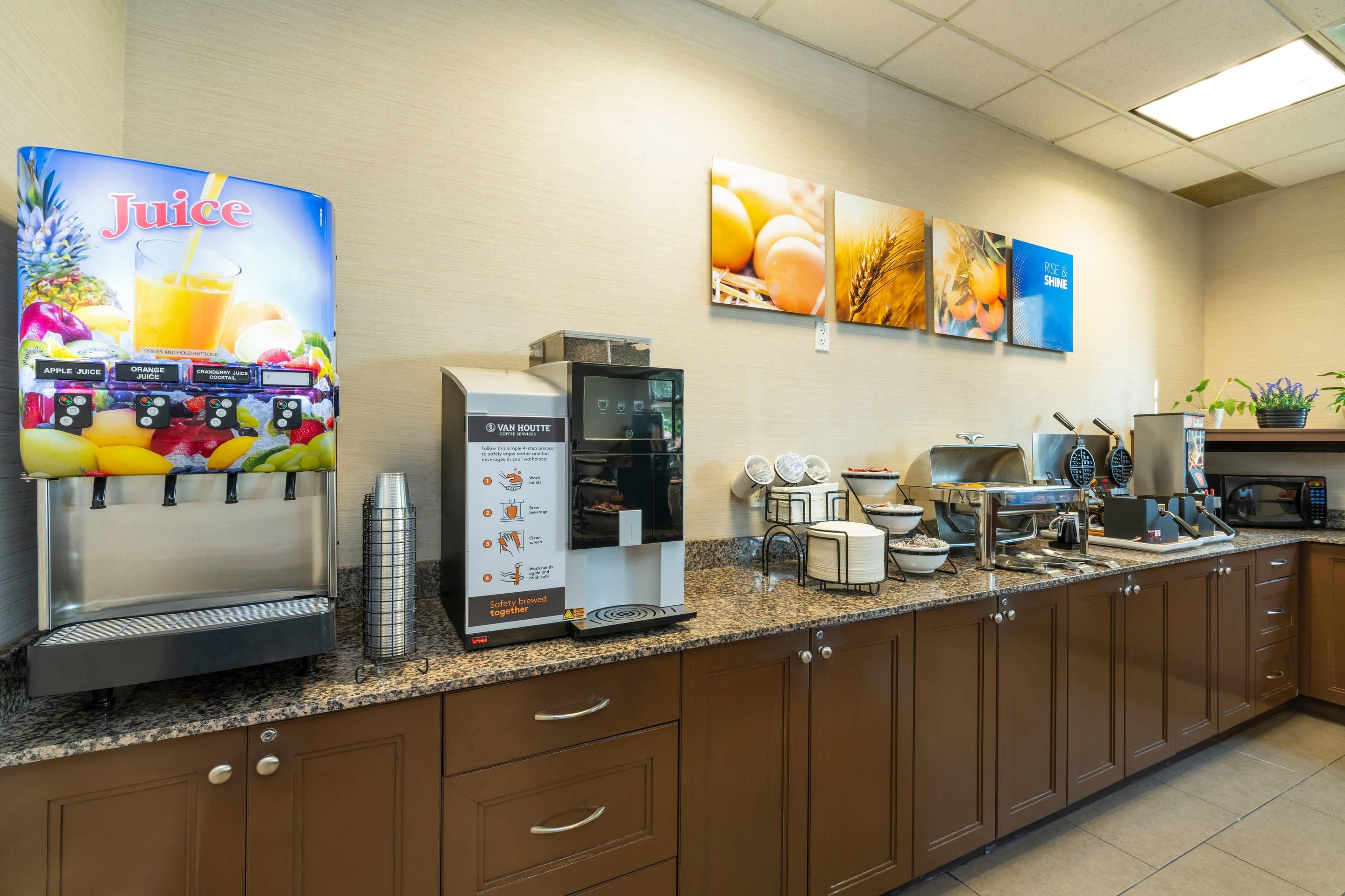 A commercial kitchen with a coffee machine, a juice dispenser, and a coffee service station.