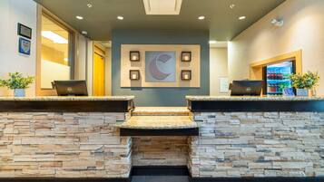 A reception area with a stone wall, a large crescent moon decoration, and two laptops on the counter.