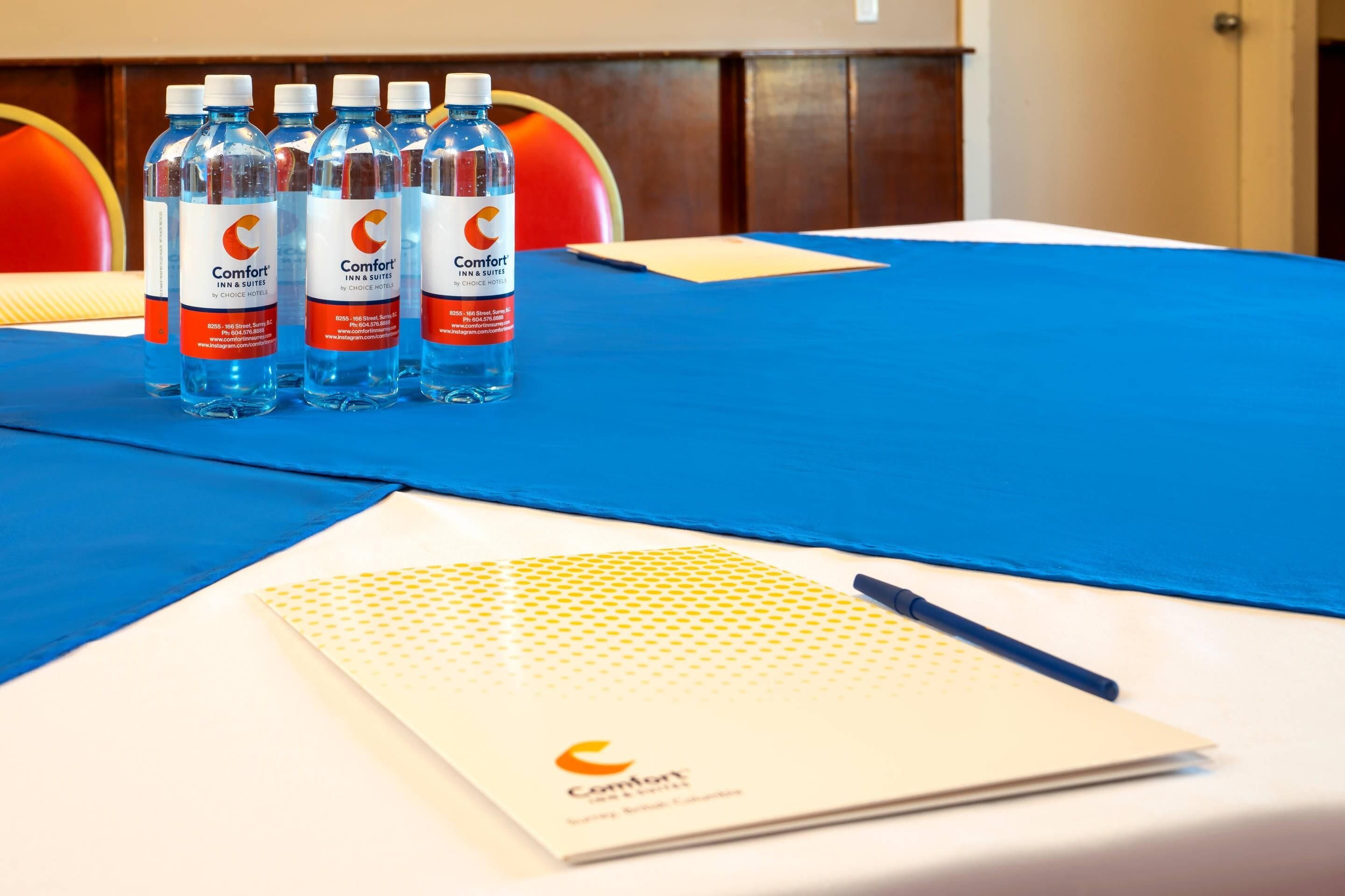 Una mesa con mantel azul, un cuaderno y cuatro botellas de agua.