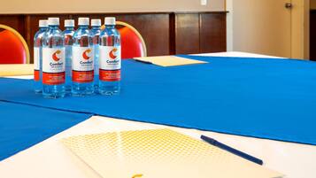 Una mesa con mantel azul, un cuaderno y cuatro botellas de agua.