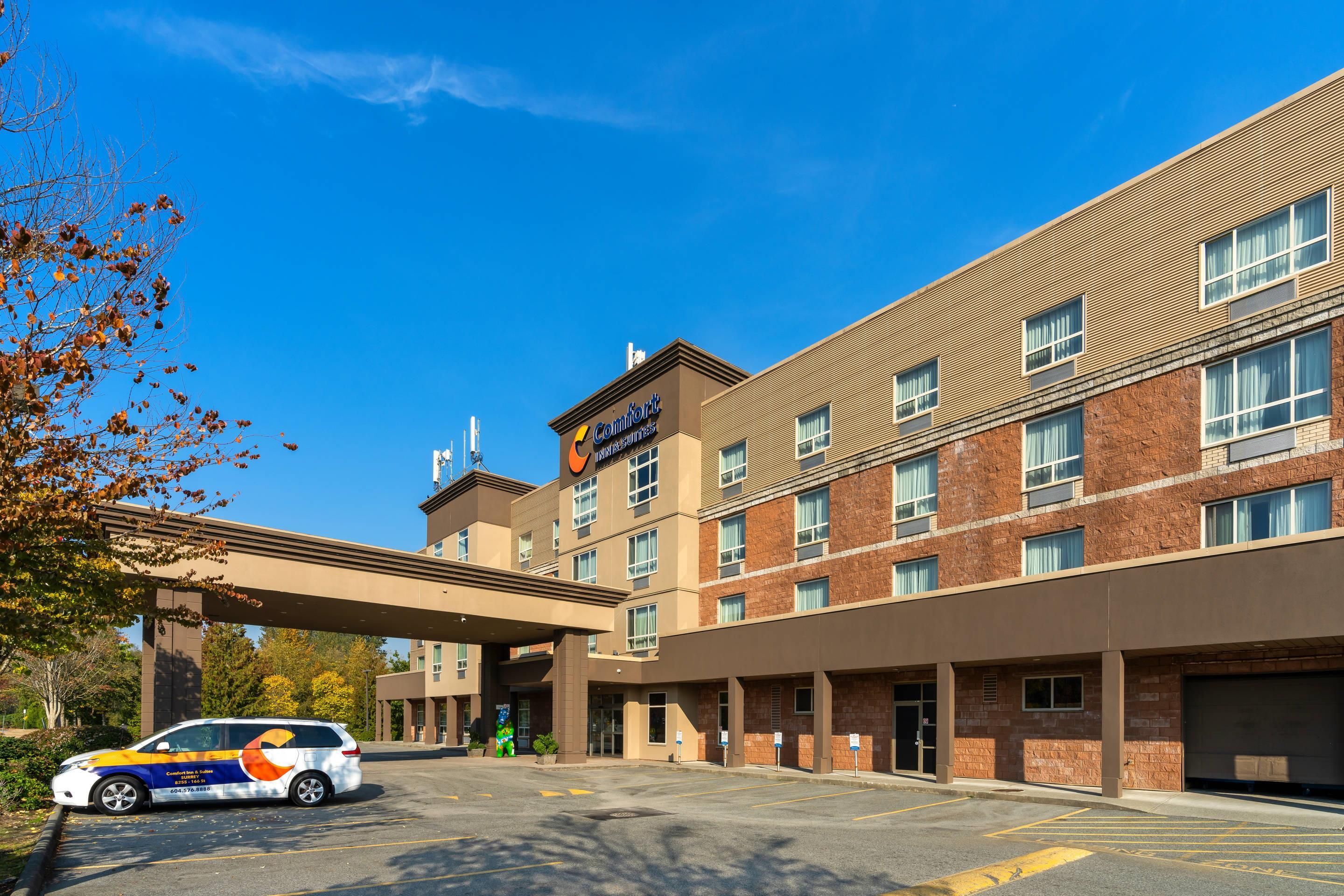 Un hotel con entrada cubierta, varias ventanas y estacionamiento.