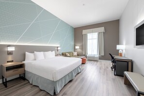 A hotel room with a large bed, bedside tables, a desk, a chair, and a TV. - Comfort Inn & Suites Surrey (Surrey)