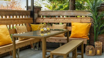 An outdoor seating area with a glass-top table, wicker furniture, and yellow cushions.