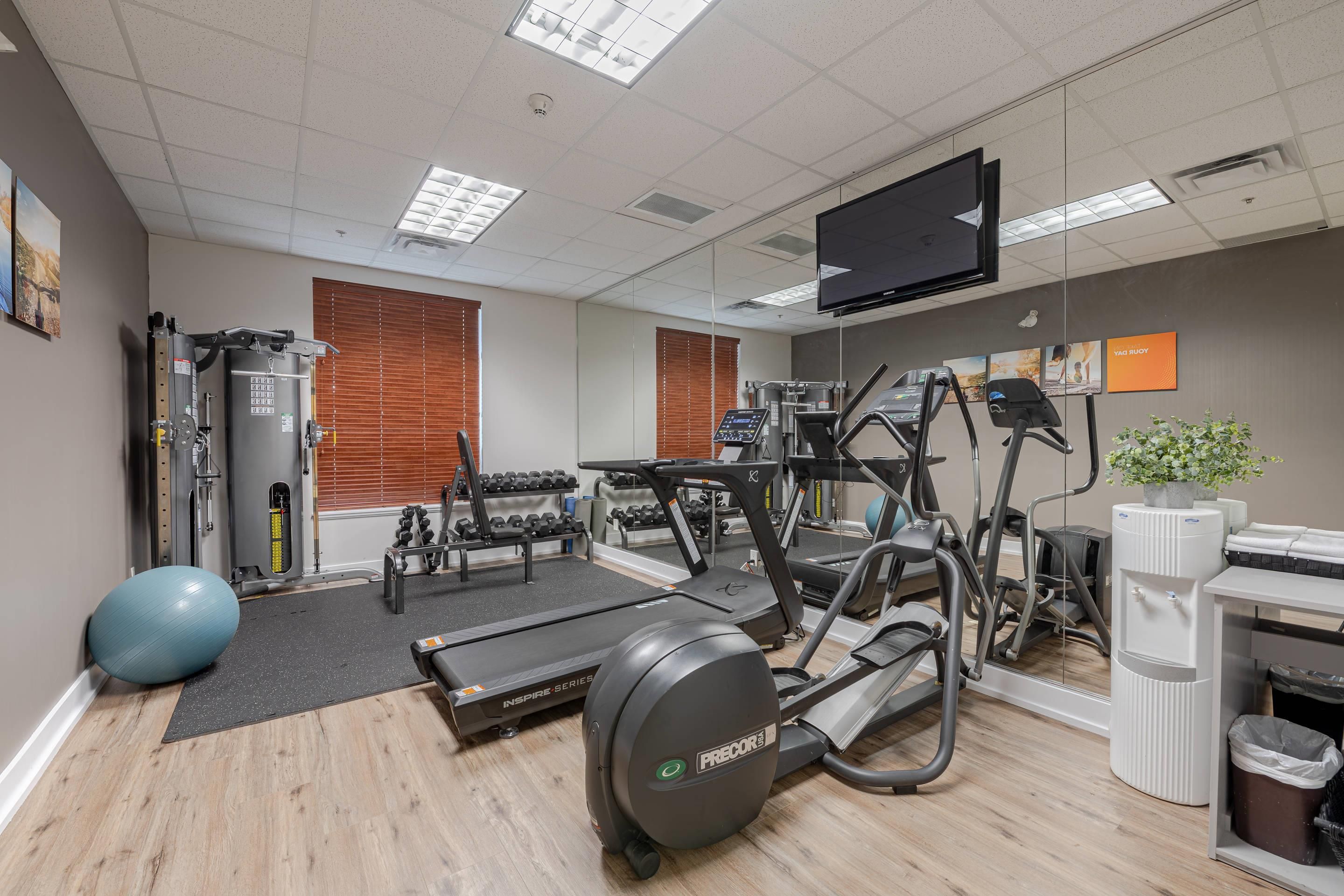 A gym with exercise equipment, a television, and a mirror.