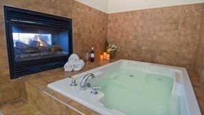 A bathroom with a bathtub, a fireplace, and a tiled wall.