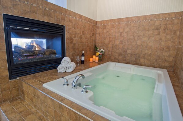 A bathroom with a bathtub, a fireplace, and a tiled wall. - Comfort Inn & Suites Surrey (Surrey)