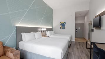 Une chambre d’hôtel avec un grand lit, un bureau, une chaise, une télévision et une porte donnant sur une autre pièce.