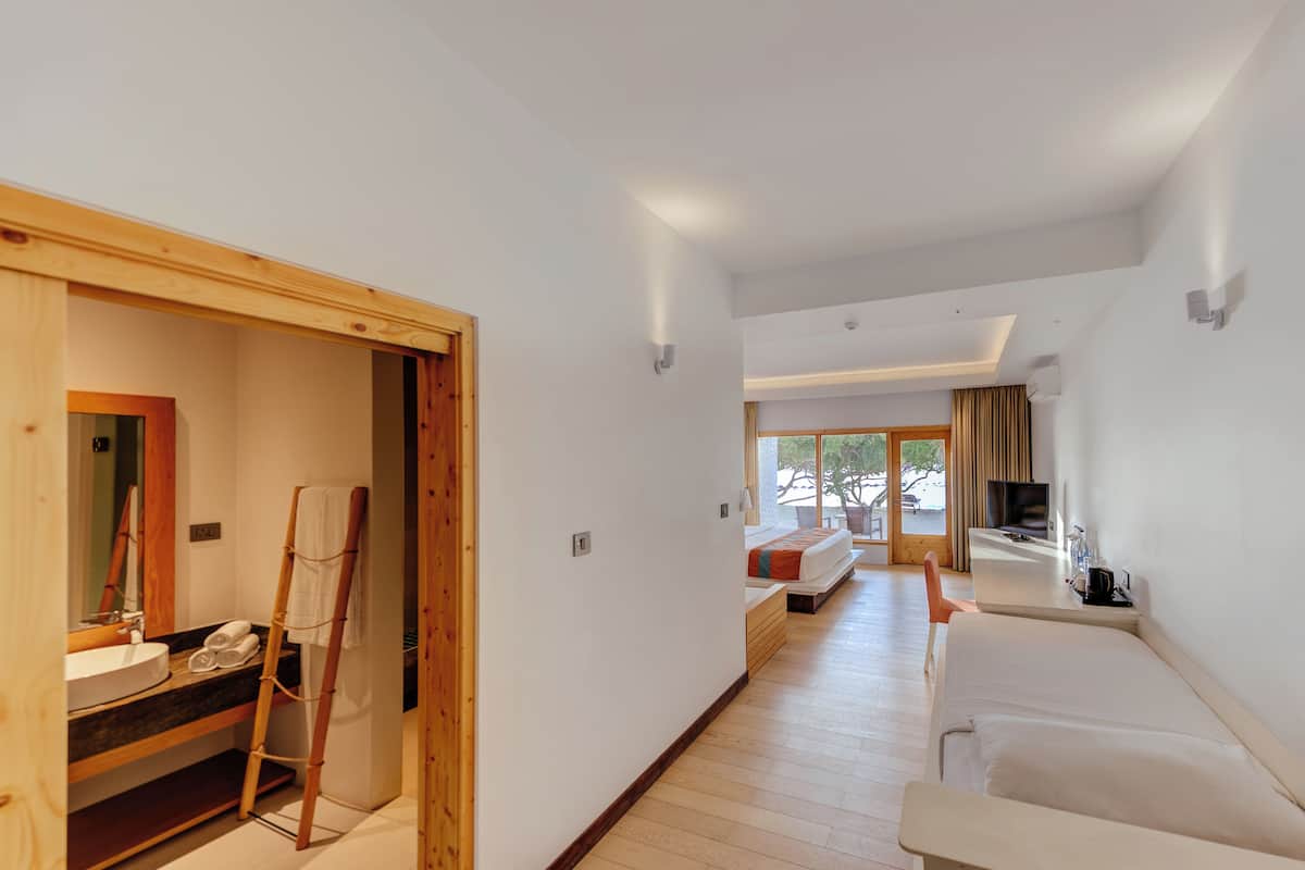 Une chambre d’hôtel moderne avec un plancher en bois, un canapé, une télévision et une salle de bain équipée d’une échelle en bois.