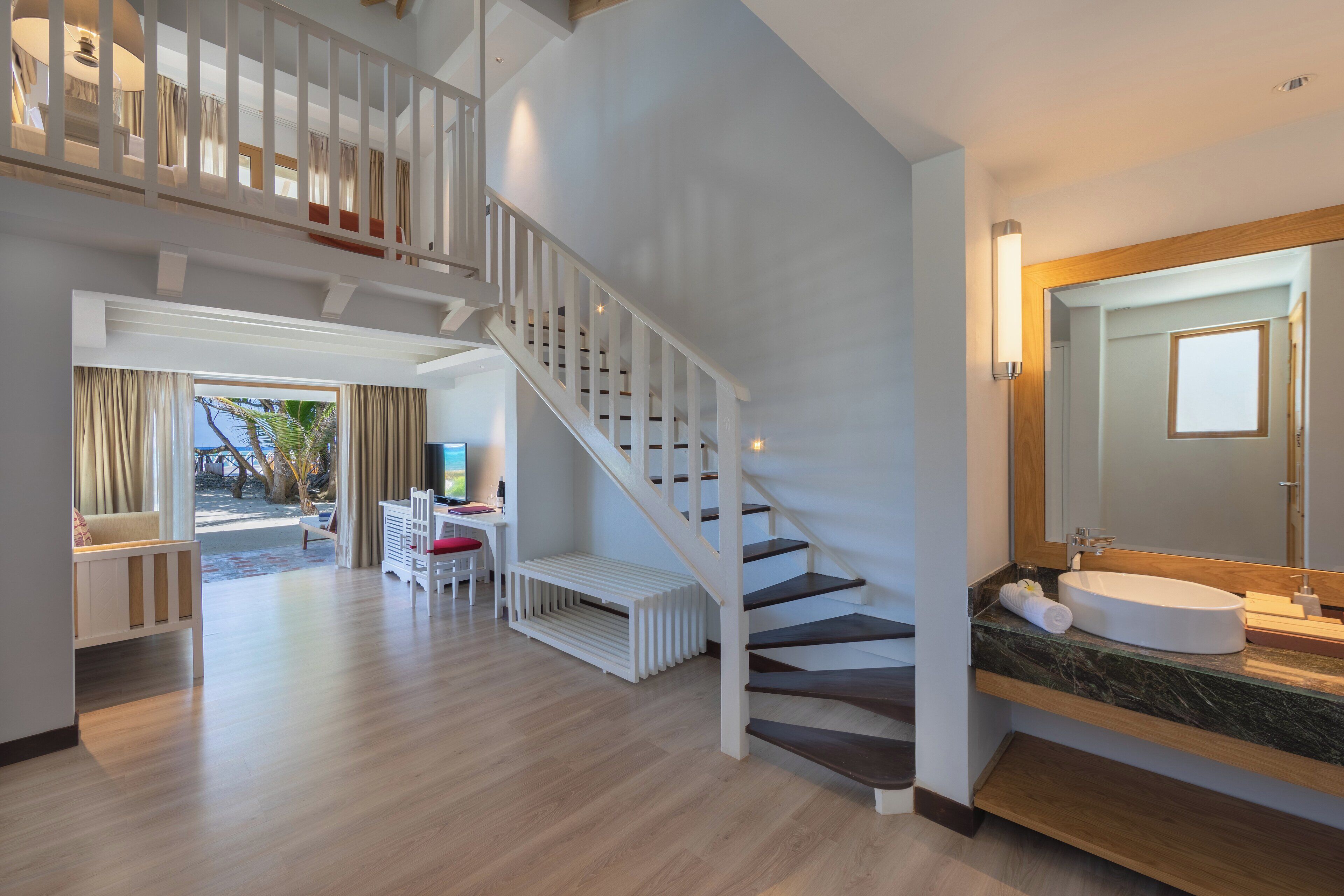 Ein großzügiger Wohnbereich mit Treppe, Balkon und modernem Badezimmer mit großem Spiegel und Waschbecken.