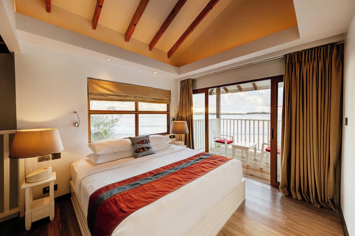 Une chambre spacieuse avec un grand lit, un balcon offrant une belle vue et un plafond en bois.