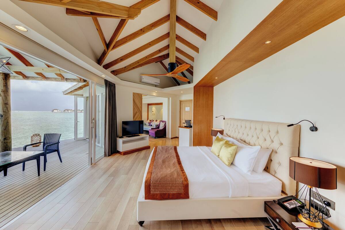Une chambre d’hôtel moderne dotée d’un grand lit, d’une télévision, d’un bureau et d’un balcon offrant une vue sur la mer.