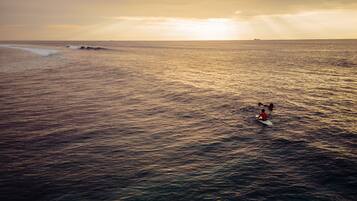 A beach scene with waves and a person surfing.