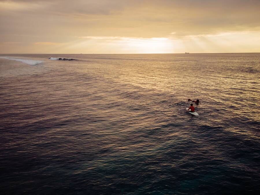 A beach scene with waves and a person surfing.