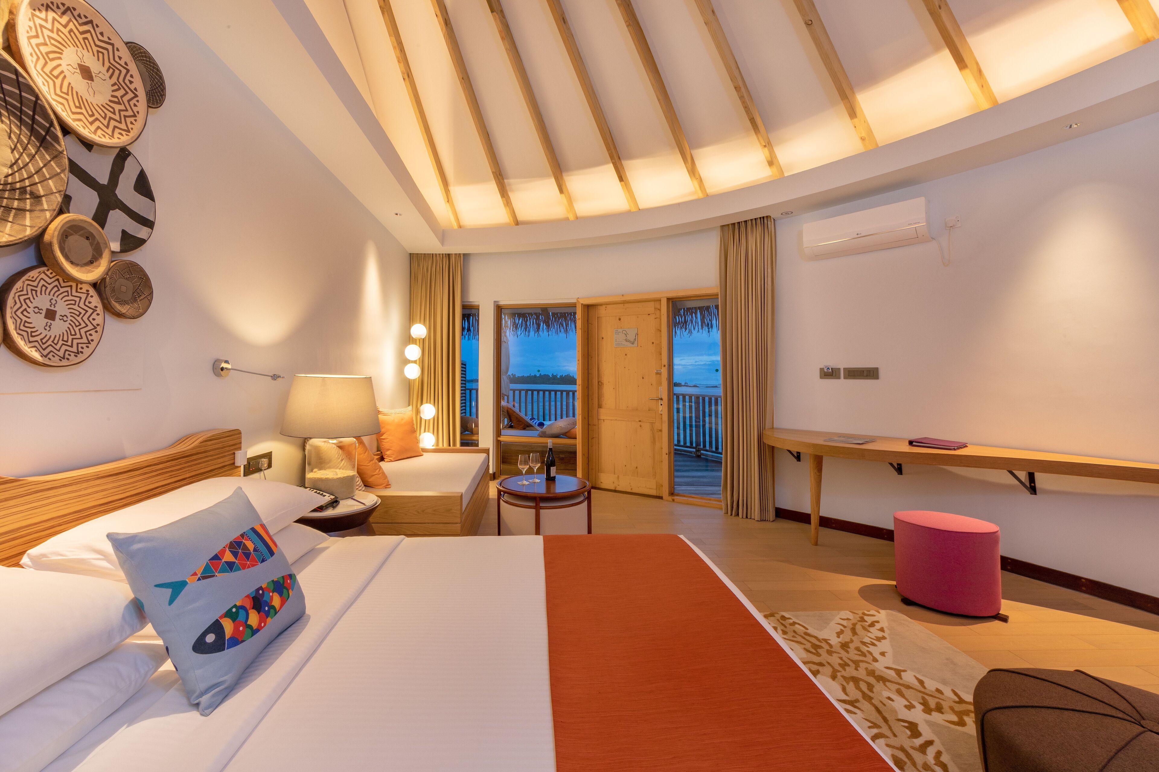 Habitación de hotel con cama, escritorio, silla, balcón y vistas al exterior.