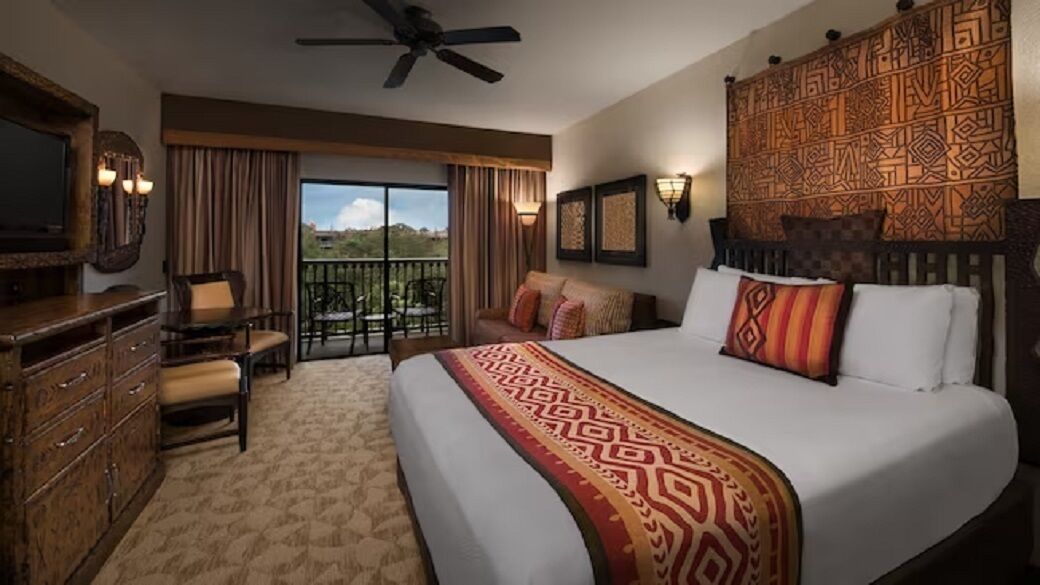 Habitación de hotel con una cama grande, televisión, escritorio y balcón con vistas.