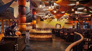 A restaurant with a central bar area, wooden pillars, and hanging woven light fixtures. - Disney's Animal Kingdom Villas - Kidani Village (Kissimmee)
