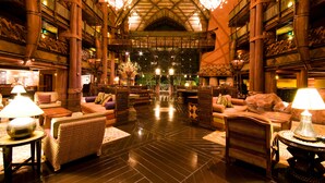 A spacious lobby with high ceilings, ornate wooden railings, and multiple seating areas.