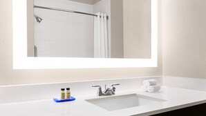 A bathroom with a white sink, a mirror, and a shower area. - Holiday Inn Express & Suites San Antonio NW - Medical Area by IHG (San Antonio)