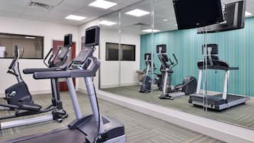 A fitness center with treadmills, elliptical machines, and a mirrored wall.