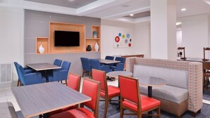 A modern hotel lobby with a seating area, a flat-screen TV, and a wall with decorative plates. - Holiday Inn Express & Suites San Antonio NW - Medical Area by IHG (San Antonio)