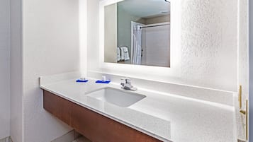 Baño con encimera blanca, lavabo y espejo.