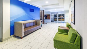 Un hall d’entrée moderne avec un mur d’accent bleu, un canapé marron et des sièges verts.