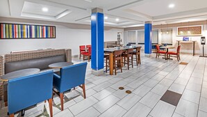 Un hall d'hôtel moderne avec un espace salon, un comptoir d'accueil et une cuisine en arrière-plan.