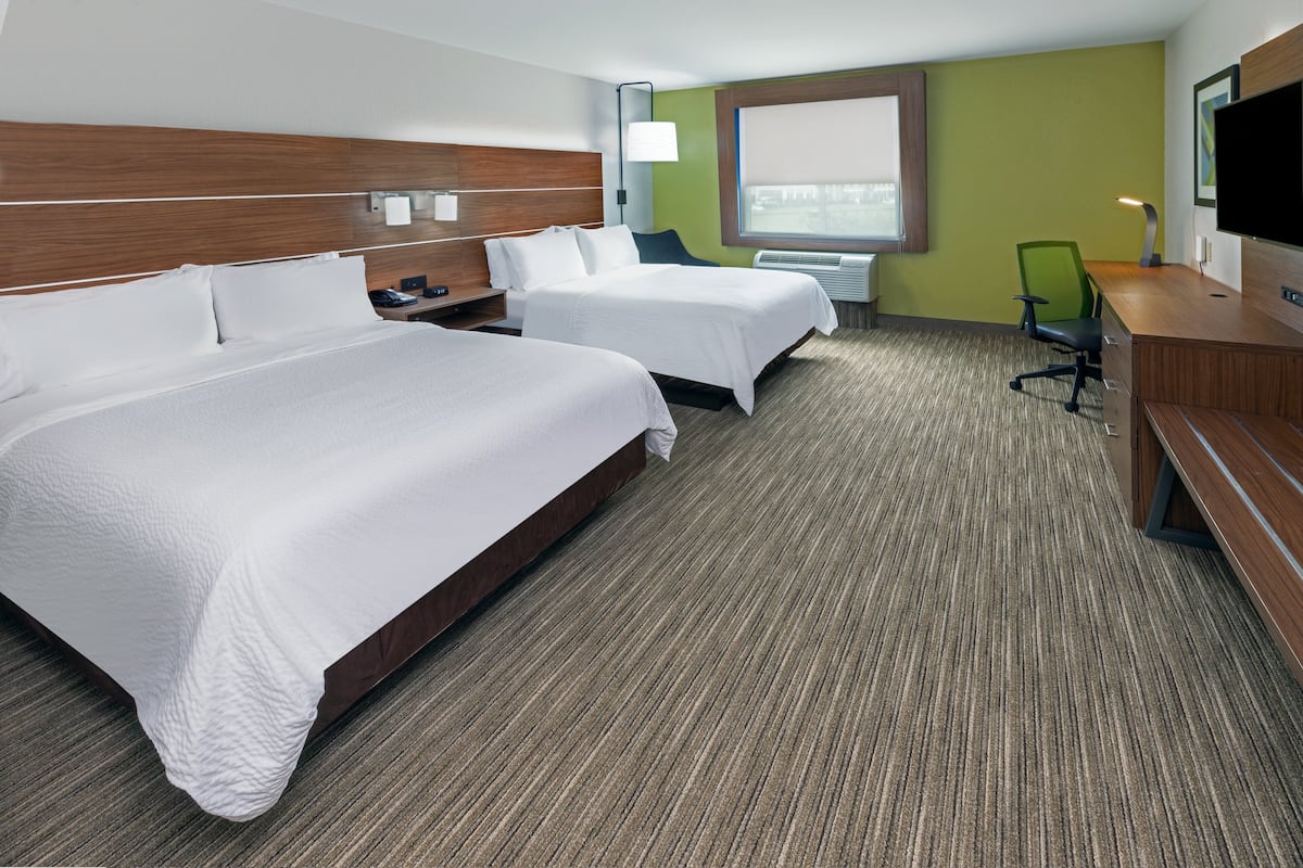 A hotel room with two beds, a desk, a chair, a TV, and a window with a view.