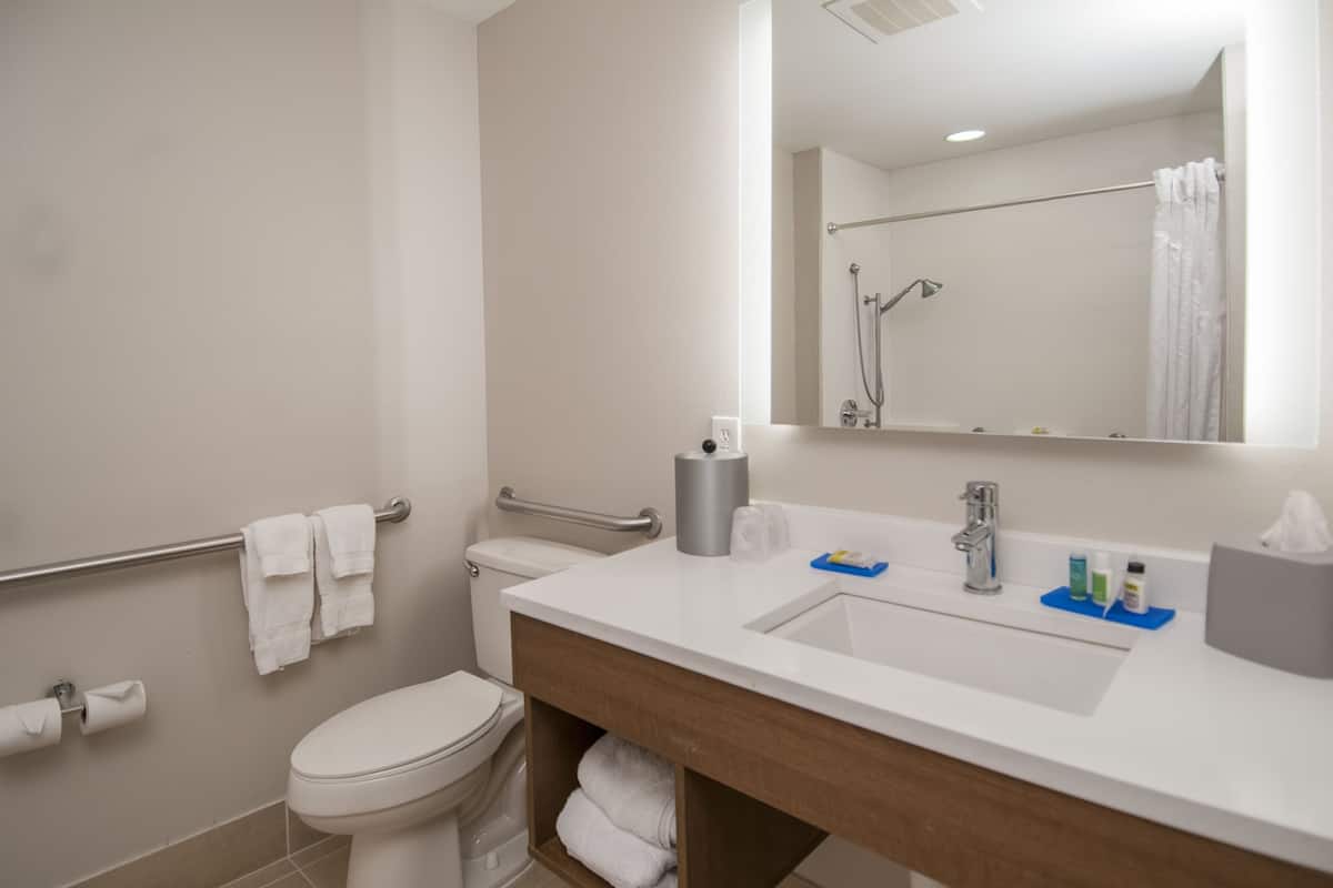 A modern bathroom with a white toilet, a sink with a mirror, and a shower area.