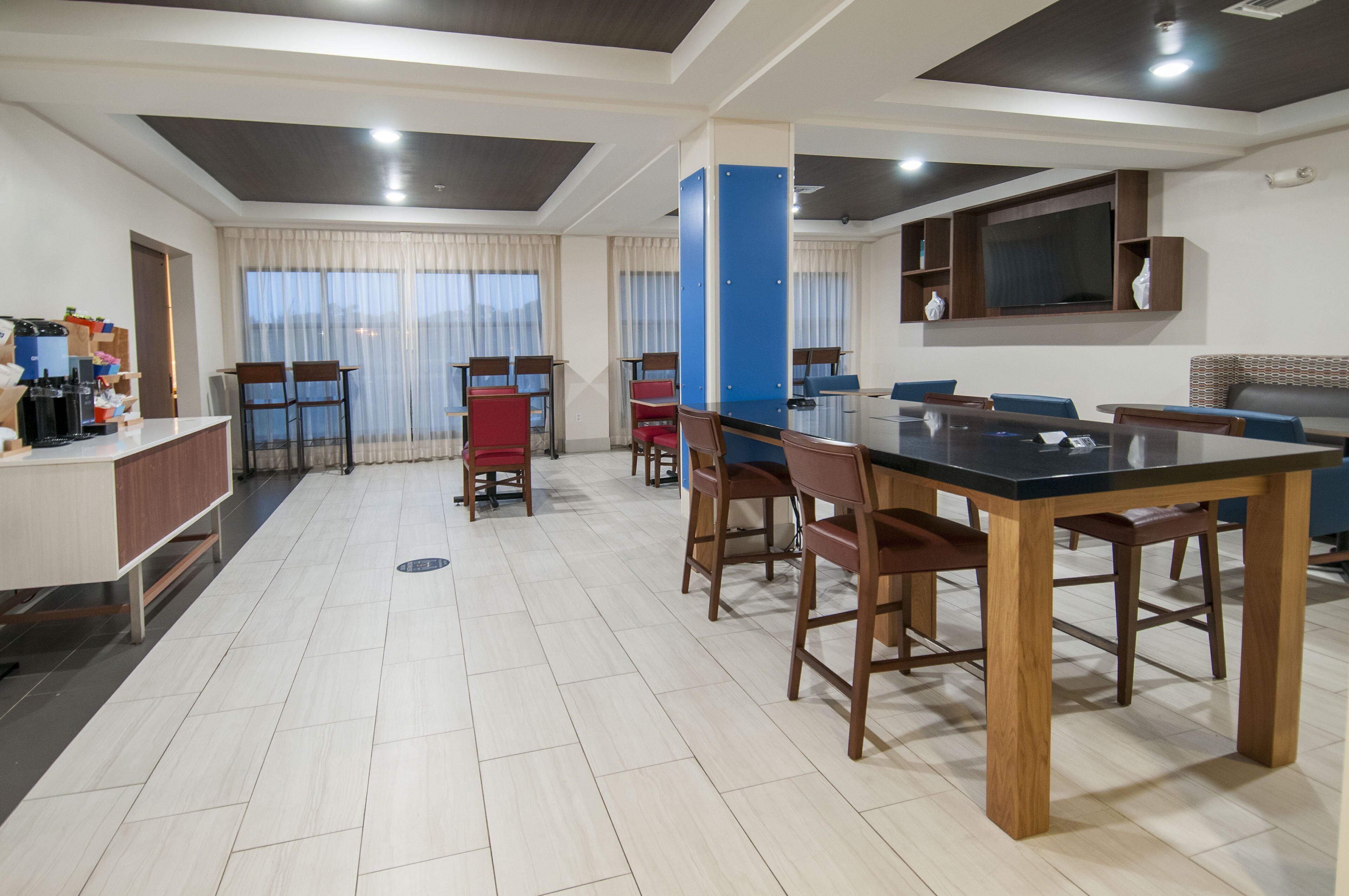 A modern hotel room with a dining area, a kitchen, and a living area.