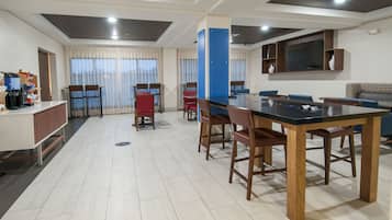 A modern hotel room with a dining area, a kitchen, and a living area.