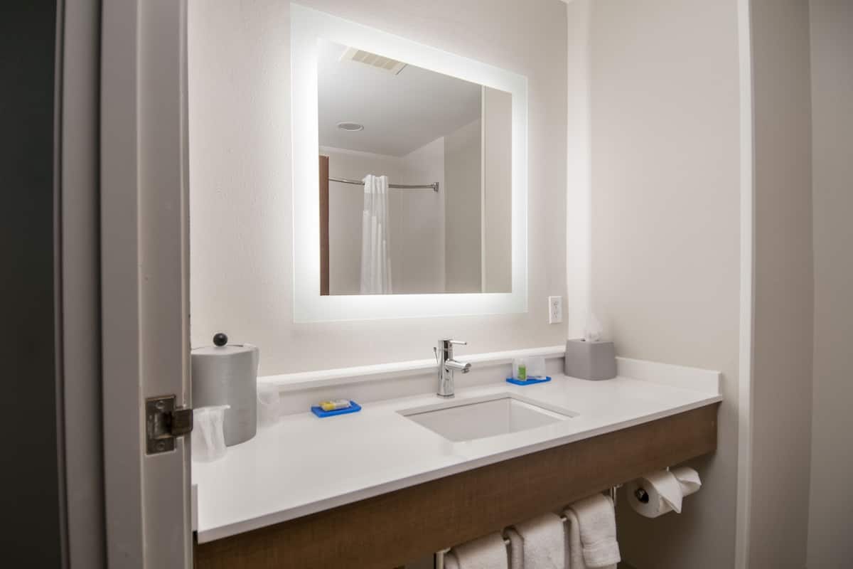 A bathroom with a white sink, a mirror, and a towel rack.