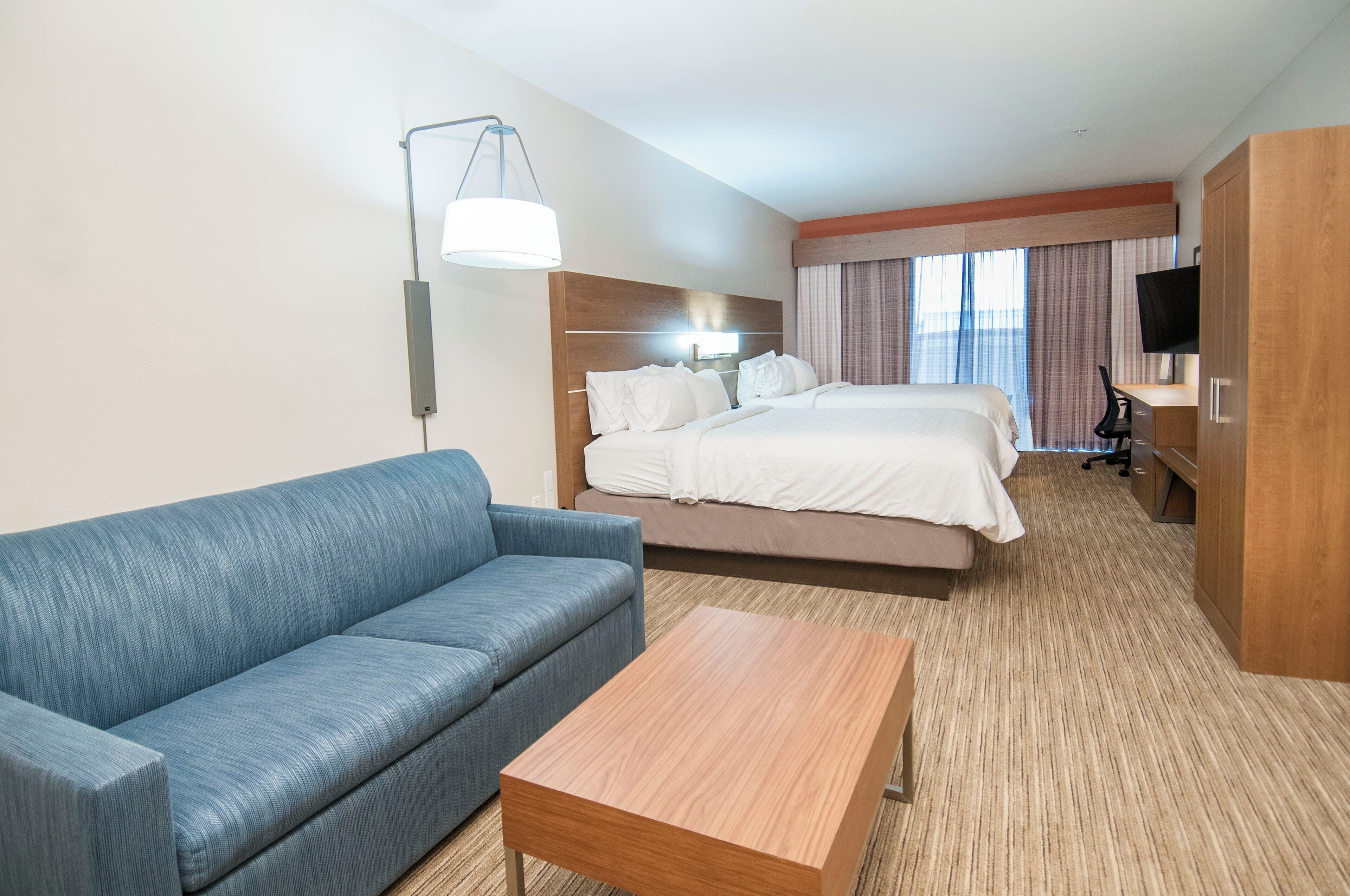 A hotel room with a bed, a sofa, a desk, and a TV.