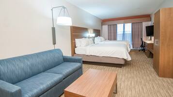A hotel room with a bed, a sofa, a desk, and a TV.