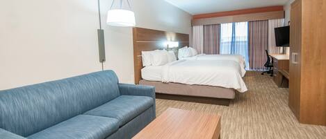 Una habitación de hotel con cama, sofá, escritorio y televisor.