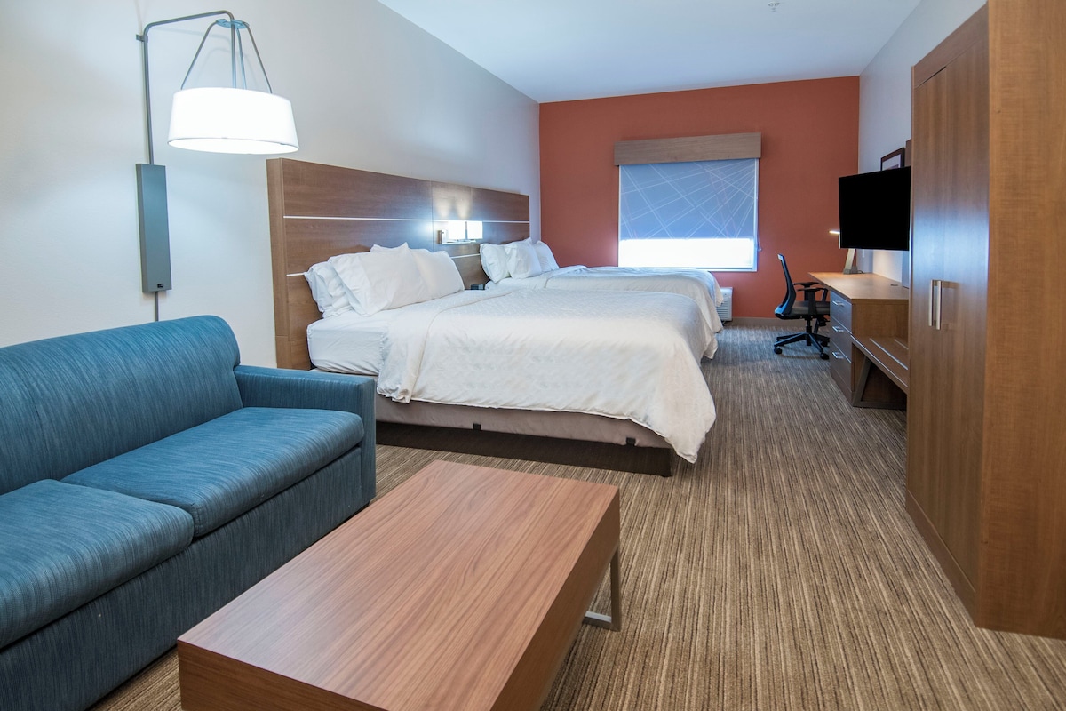 Una habitación de hotel con cama, sofá, escritorio, televisor y lámpara.