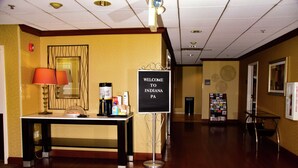 A hotel lobby with a reception desk, a welcome sign, a coffee station, and a bulletin board. - Hampton Inn Indiana (Indiana)