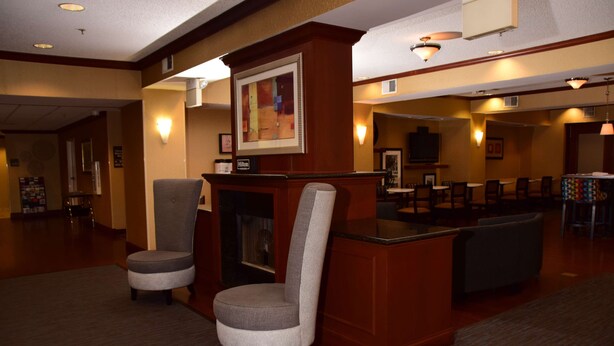A lobby with a reception desk, two armchairs, and a dining area with tables and chairs. - Hampton Inn Indiana (Indiana)