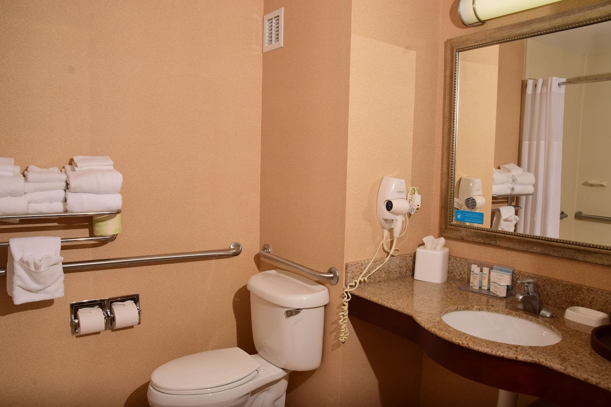 A bathroom with a toilet, hand dryer, towel rack, and sink.