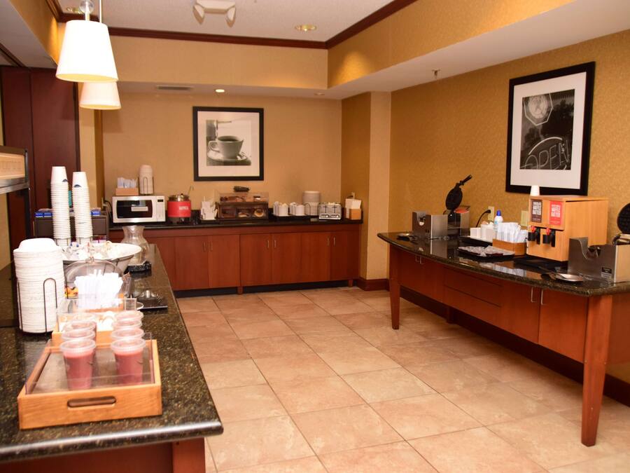 Cocina de hotel con barra de buffet, que incluye una estación de café, microondas y diferentes alimentos.
