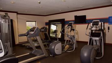 Et fitnesscenter med løbebånd, crosstrainere og en motionscykel.