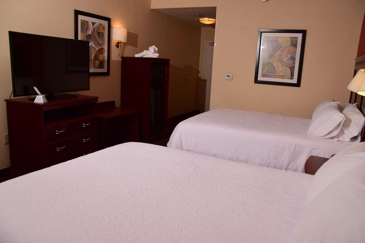 A hotel room with two beds, a TV, a desk, and a wardrobe.