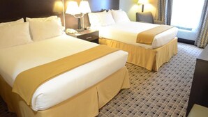 Une chambre d’hôtel avec deux lits, chacun agrémenté de draps blancs et d’un plaid beige. On y trouve des lampes de chevet et une table de chevet avec un téléphone. La chambre est dotée d’une moquette à motifs et d’une fenêtre avec des rideaux.