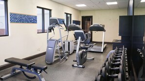 Un gimnasio con cintas de correr, elípticas, una banca y mancuernas.