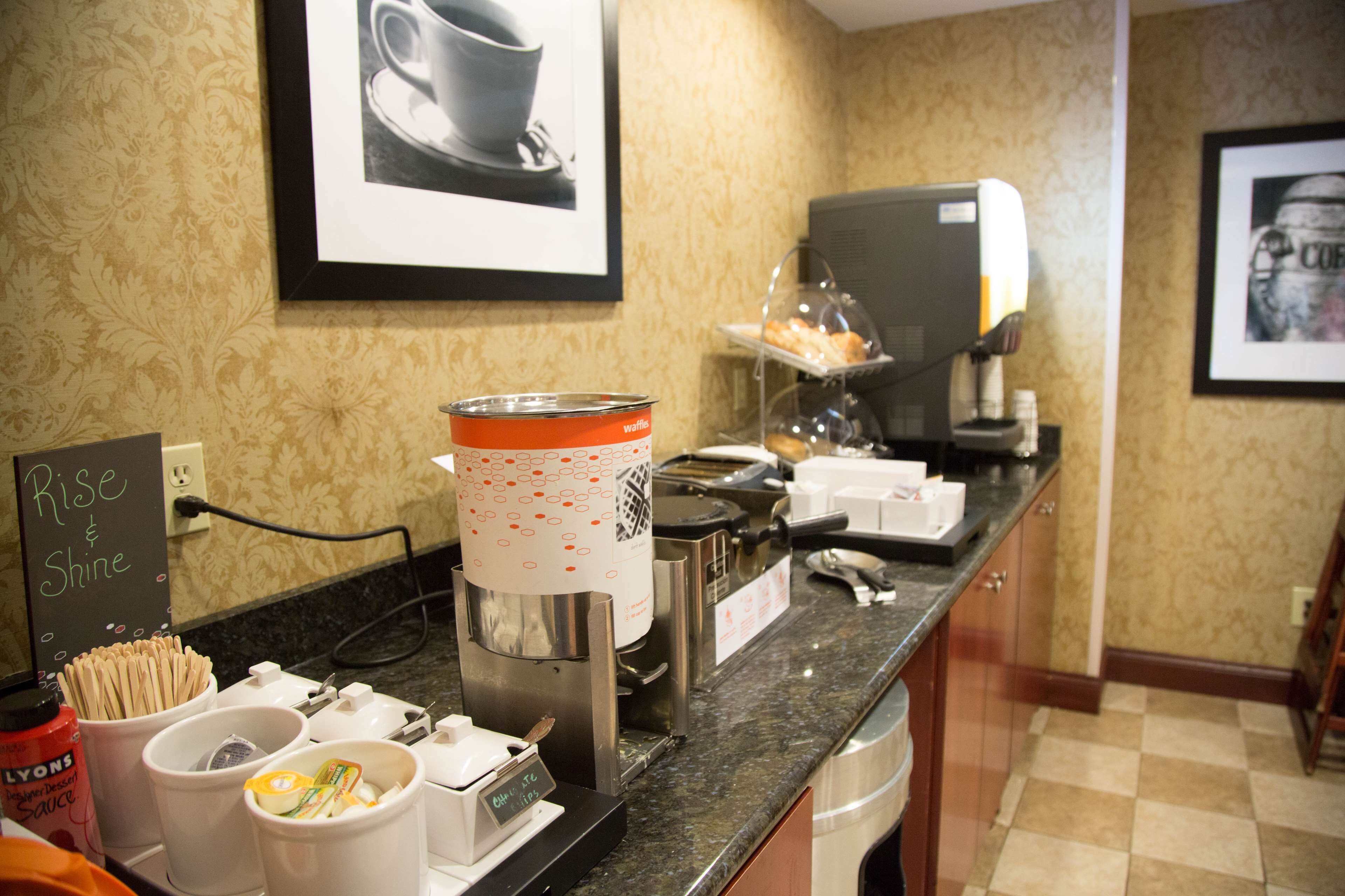 Un coin café équipé d’un appareil à gaufres, d’une machine à café et de gobelets à gaufres.