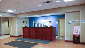 Zona de recepción con un mostrador de madera, pared azul y una puerta al fondo.